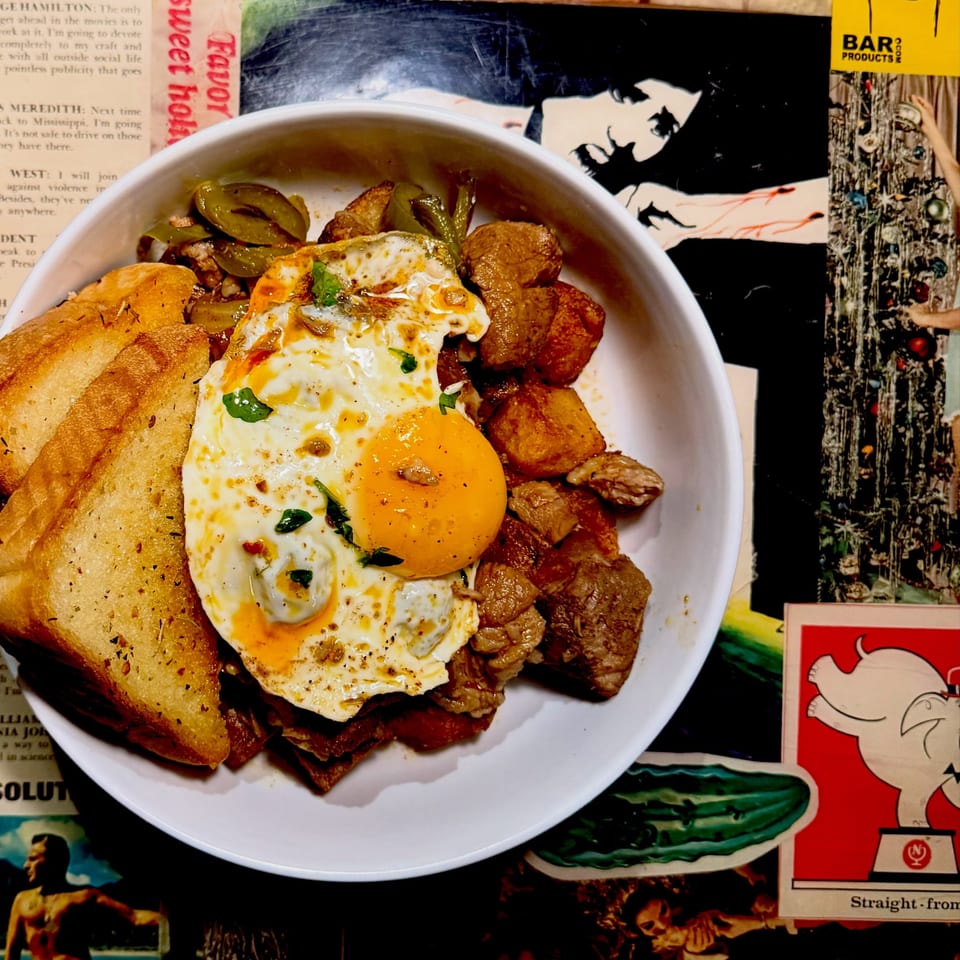 A breakfast bowl with fried eggs, meat, potatoes, green peppers, and toast on a colorful collage background.